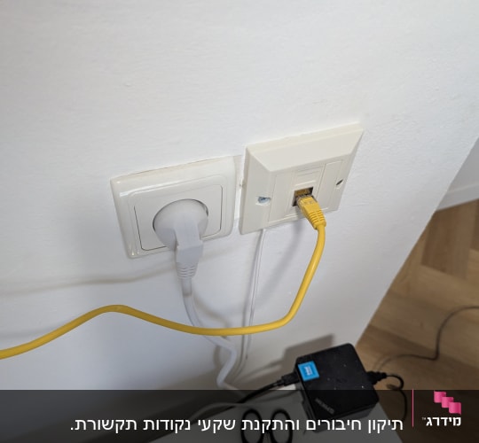 כבל רשת מחובר לשקע בקיר עם ציוד טכני נוסף